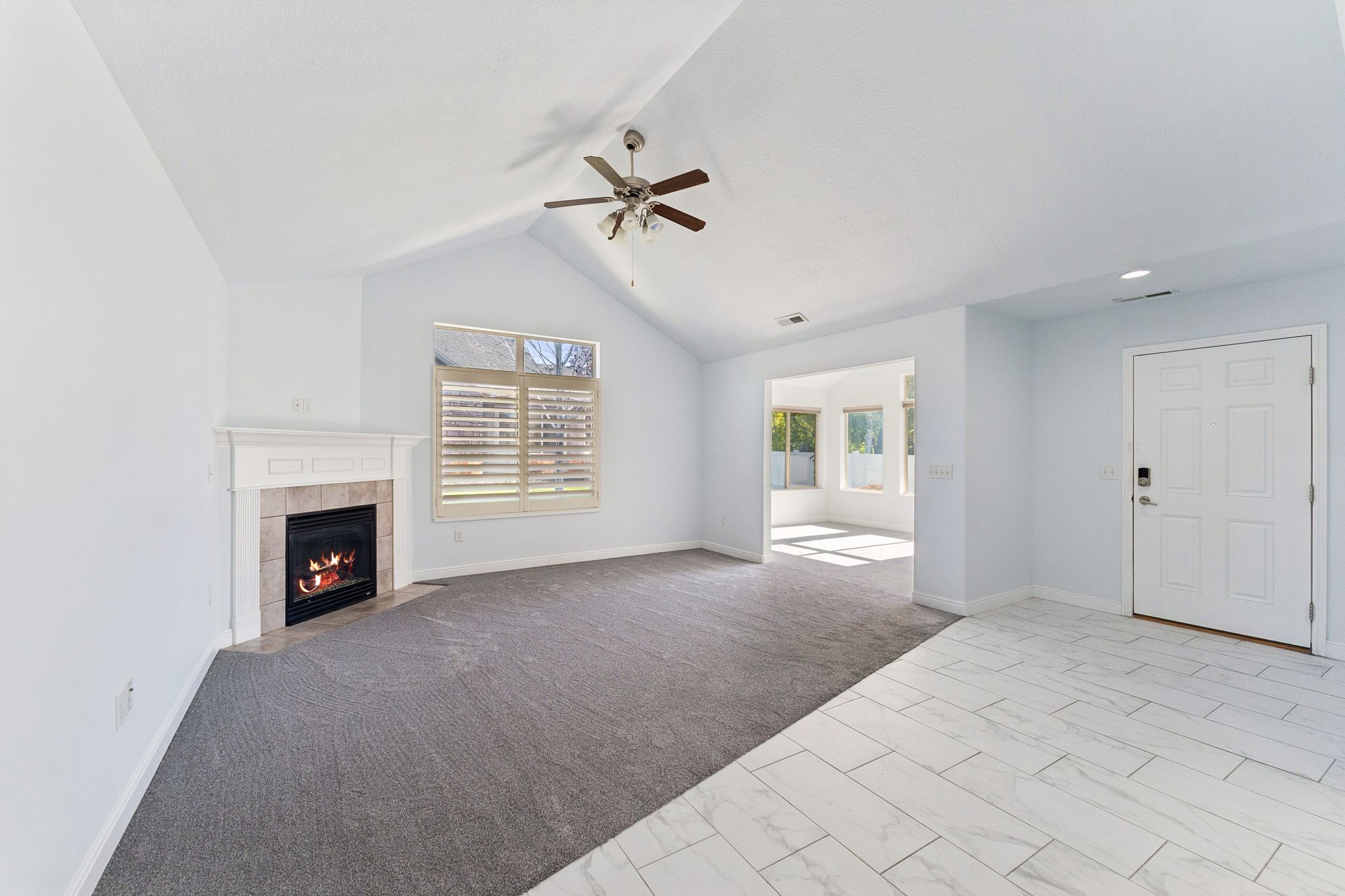 Unfurnished living room featuring light carpet, a ceiling fan, and a tile fireplace