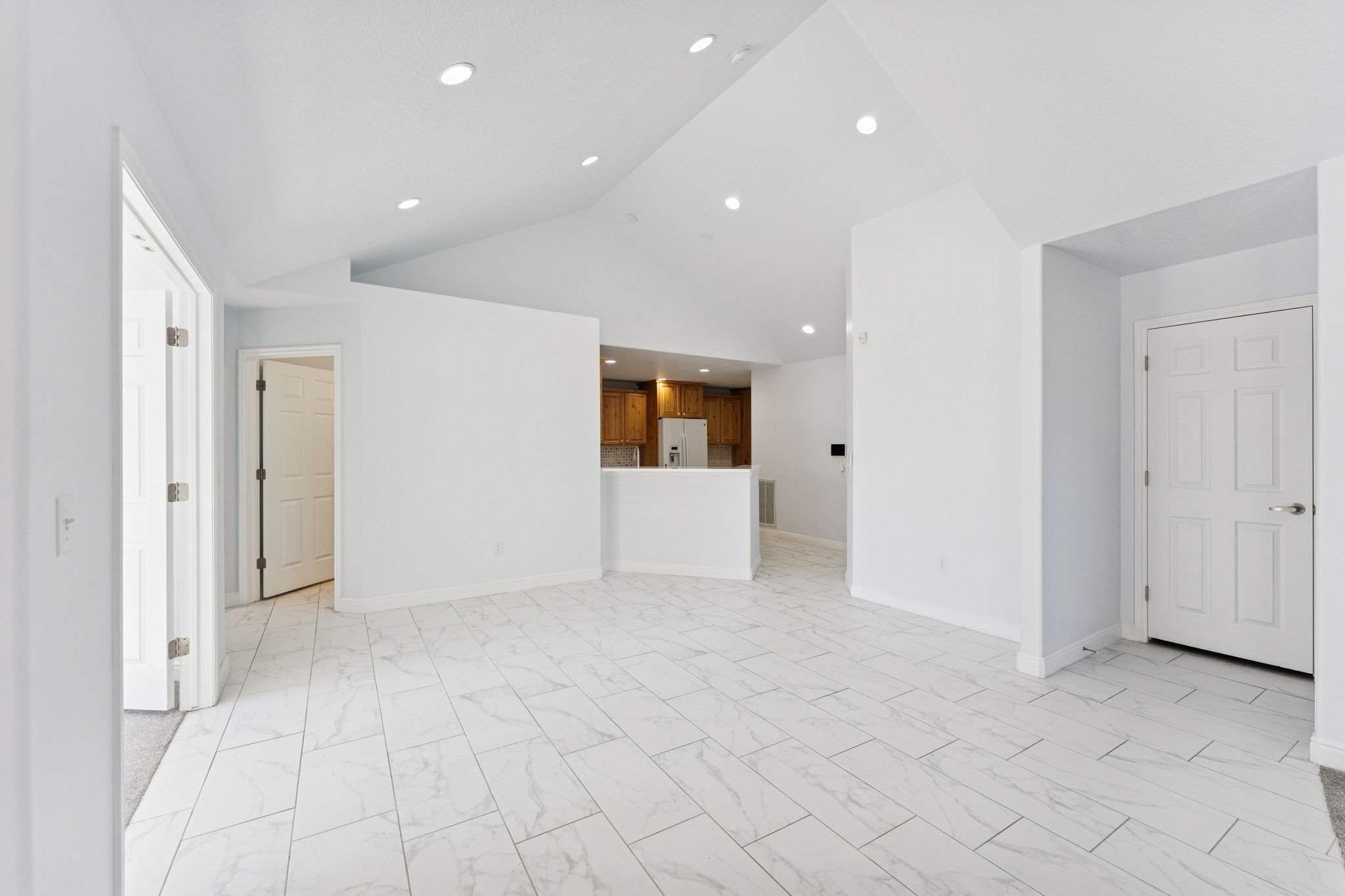 Unfurnished living room featuring light marble finish flooring, vaulted ceiling, and recessed lighting