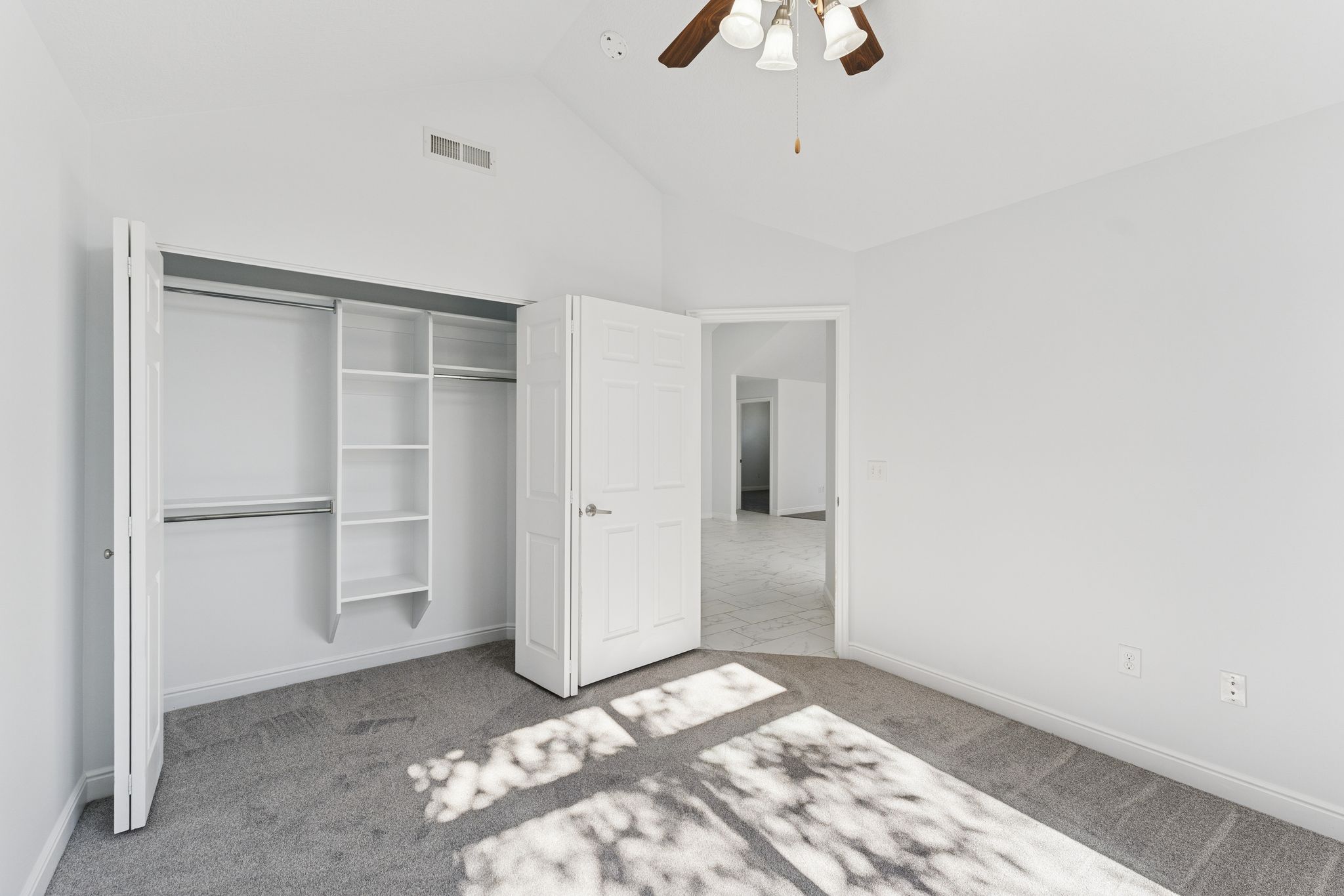 Unfurnished bedroom with vaulted ceiling, a closet, ceiling fan, and light carpet