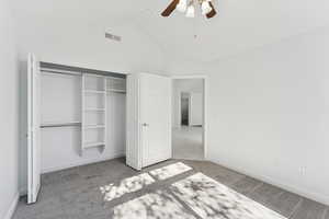 Unfurnished bedroom with vaulted ceiling, a closet, ceiling fan, and light carpet