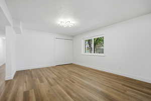 Unfurnished bedroom featuring light wood-type flooring, a closet, and a textured ceiling
