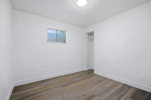 Unfurnished bedroom featuring a closet and dark wood finished floors