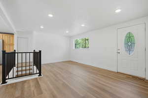 Foyer entrance with light wood-style floors and recessed lighting