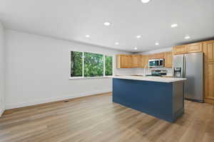 Kitchen featuring stainless steel appliances, a kitchen island with sink, light wood-style flooring, recessed lighting, and light wood finish cabinetry