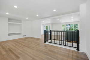 Empty room with built in features, light wood finished floors, and recessed lighting
