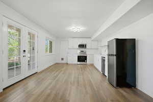 Kitchen featuring stainless steel appliances, white cabinetry, french doors, light countertops, and light wood finished floors