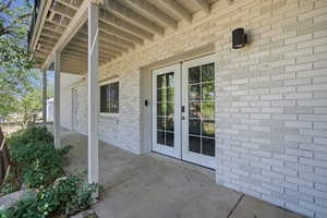 Doorway to property featuring brick siding and french doors
