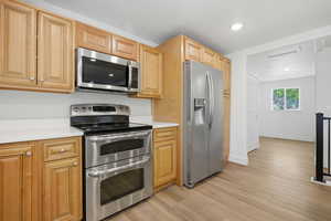 Kitchen featuring stainless steel appliances, light countertops, and light wood-style flooring