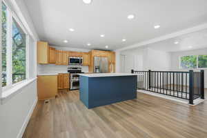 Two tone kitchen with a center island, light countertops, stainless steel appliances, recessed lighting, and light wood-type flooring