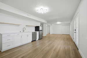 Kitchen with open shelves, light countertops, light wood finished floors, stainless steel appliances, and white cabinets
