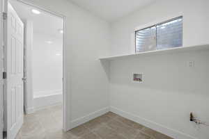 Laundry area featuring washer hookup and light tile patterned floors