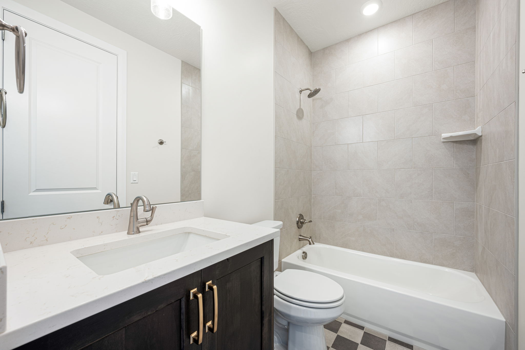 Bathroom featuring a dark wood-finish vanity with gold-tone hardware, white countertop with integrated sink, and brushed nickel faucet