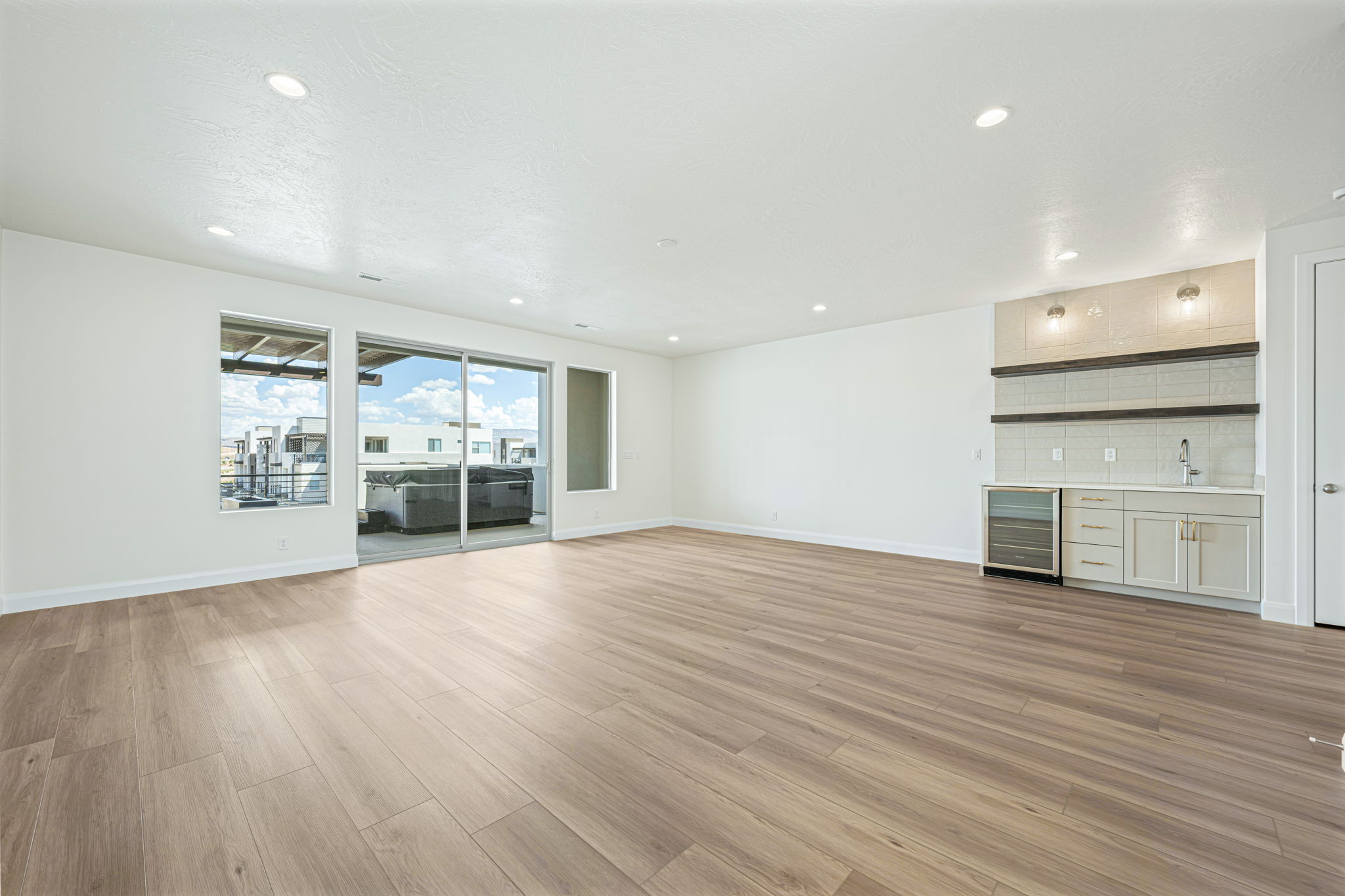 Spacious room featuring wood-finish flooring, recessed lighting, and a built-in wet bar with a beverage cooler