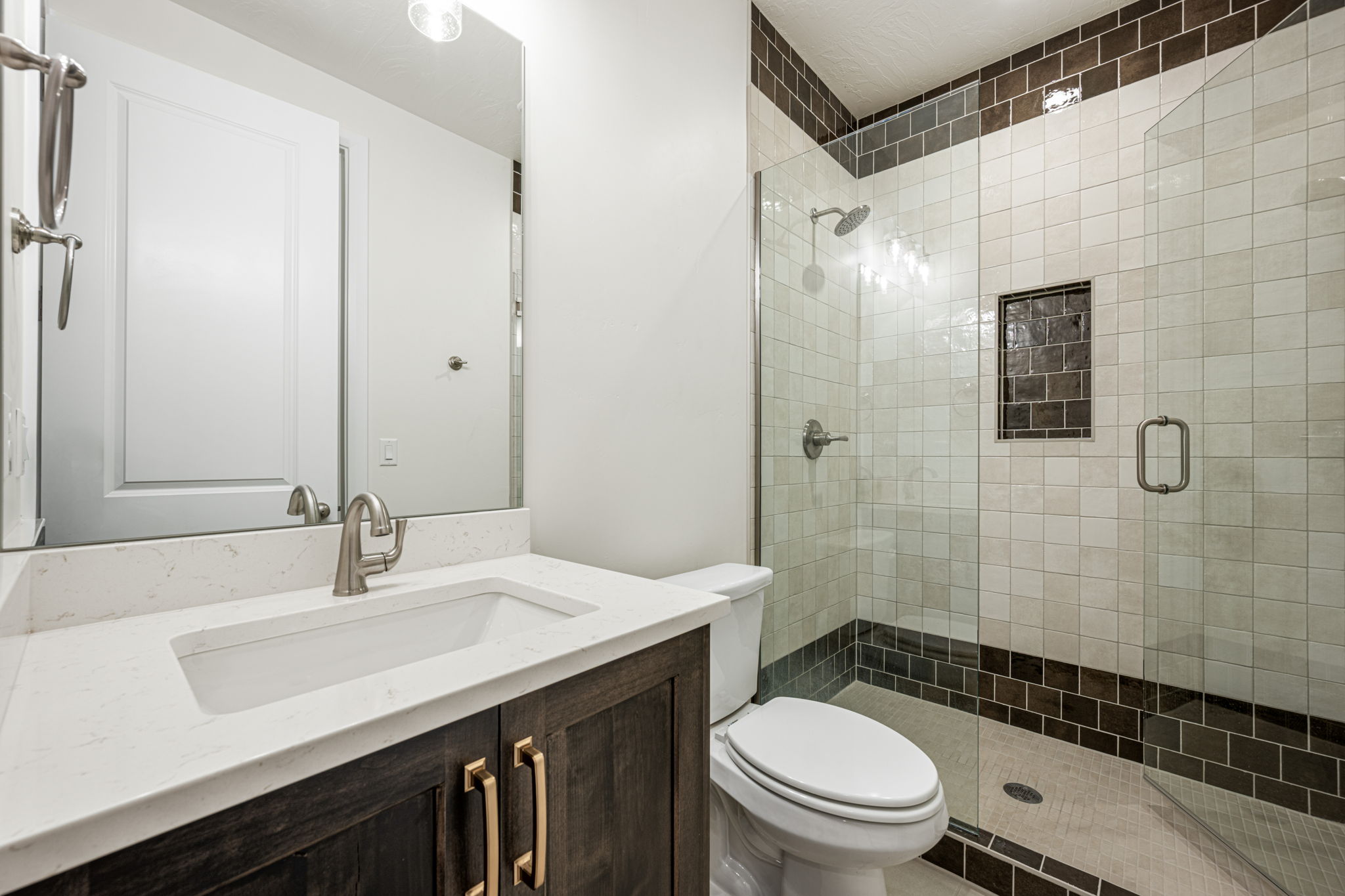 Spacious bathroom featuring a dark wood-finish vanity with gold-tone hardware, a white countertop, and an undermount sink