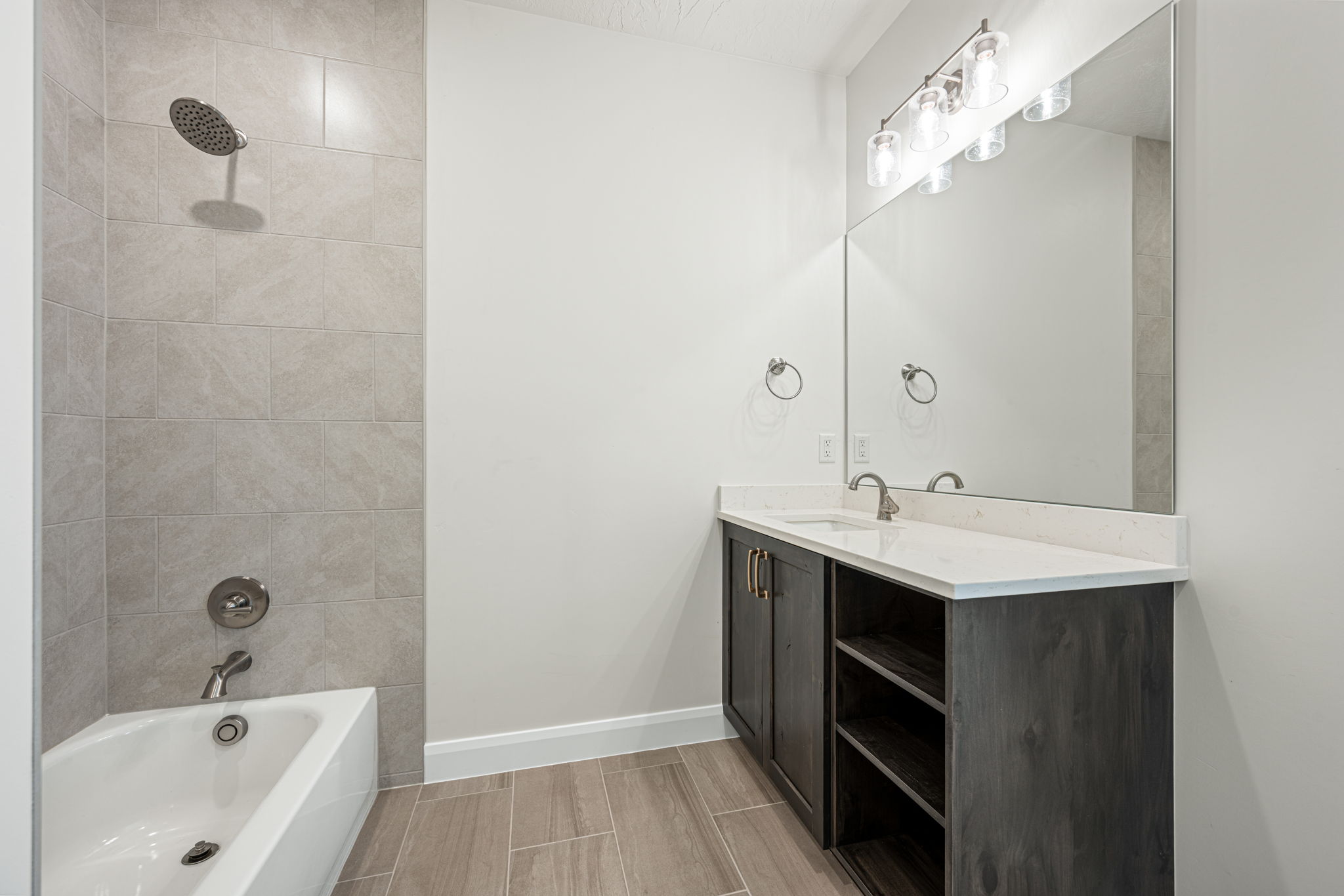 Bathroom featuring a single vanity with a white countertop, dark wood-finish cabinetry, and an integrated rectangular sink