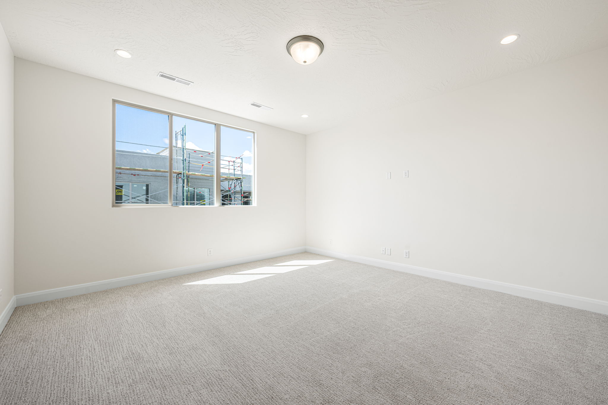 Bright room featuring a three-panel window, light textured carpet, recessed lighting, and a flush-mount ceiling fixture