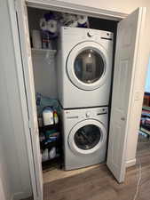 Laundry area with light wood-style flooring and stacked washer / drying machine