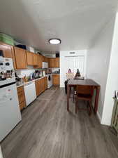 Kitchen with white appliances, light countertops, a textured ceiling, dark wood-style flooring, and wood finish cabinetry