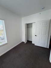 Unfurnished bedroom featuring dark carpet and a closet