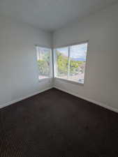 Spare room with dark carpet and a textured ceiling