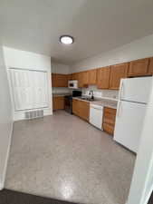 Kitchen with white appliances, light countertops, and wood finish cabinets