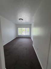 Empty room featuring a textured ceiling and dark colored carpet
