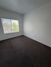 Unfurnished room with dark carpet and a textured ceiling