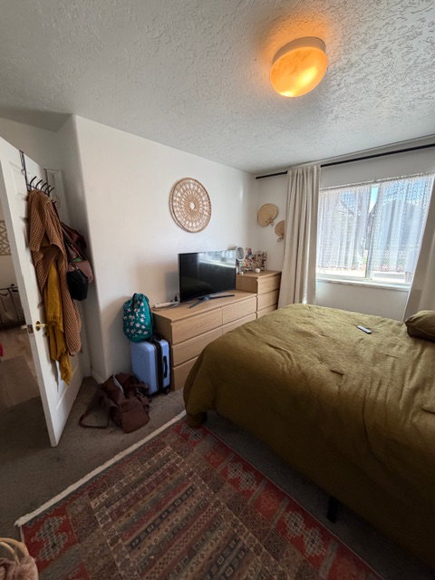 Bedroom featuring a textured ceiling and dark carpet
