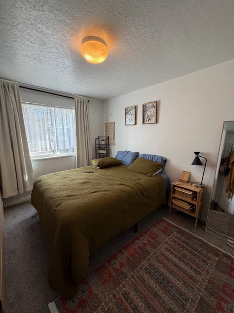 Bedroom with a textured ceiling and dark carpet