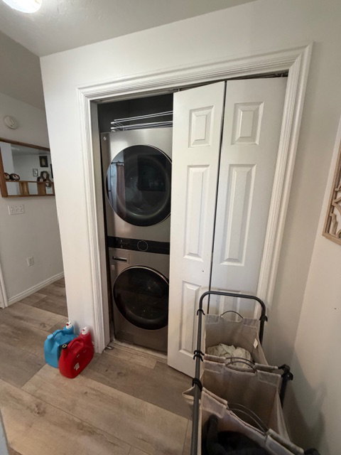 Laundry area featuring stacked washing machine and dryer and light wood finished floors