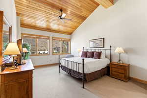 Bedroom with light colored carpet, ceiling fan, and a vaulted wood ceiling