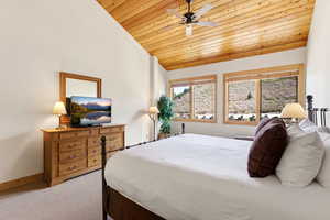 Bedroom with light colored carpet, a vaulted wood ceiling, and ceiling fan