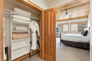Bedroom featuring wood ceiling, light colored carpet, and a closet