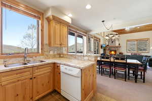 Kitchen with light stone countertops, open floor plan, white dishwasher, a chandelier, and light wood finish cabinetry