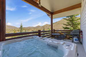 View of patio featuring a hot tub, a mountain view, and grilling area