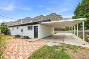 View of side of property featuring a mountain view, a carport, brick siding, and a patio area