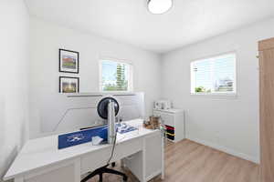 Home office with light wood-style floors and baseboards