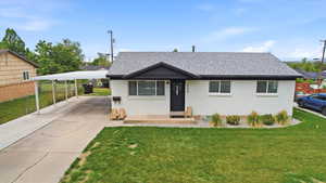View of front of home with a front yard, roof with shingles, and brick siding