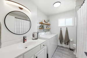 Bathroom with vanity, independent washer and dryer, and curtained shower