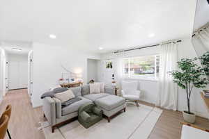 Living area with light wood-style flooring and recessed lighting