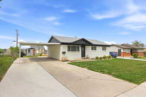 Ranch-style home featuring an attached carport, concrete driveway, and a front yard
