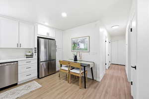 Kitchen featuring white cabinets, stainless steel appliances, light wood-style flooring, and recessed lighting