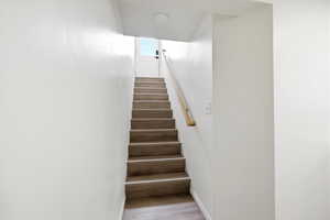 Stairway with wood finished floors and baseboards