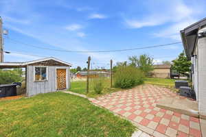 Fenced backyard featuring a storage unit and a patio