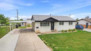 View of front of home featuring an attached carport, a shingled roof, brick siding, and driveway