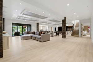 Living area featuring a raised ceiling, light wood-type flooring, and recessed lighting