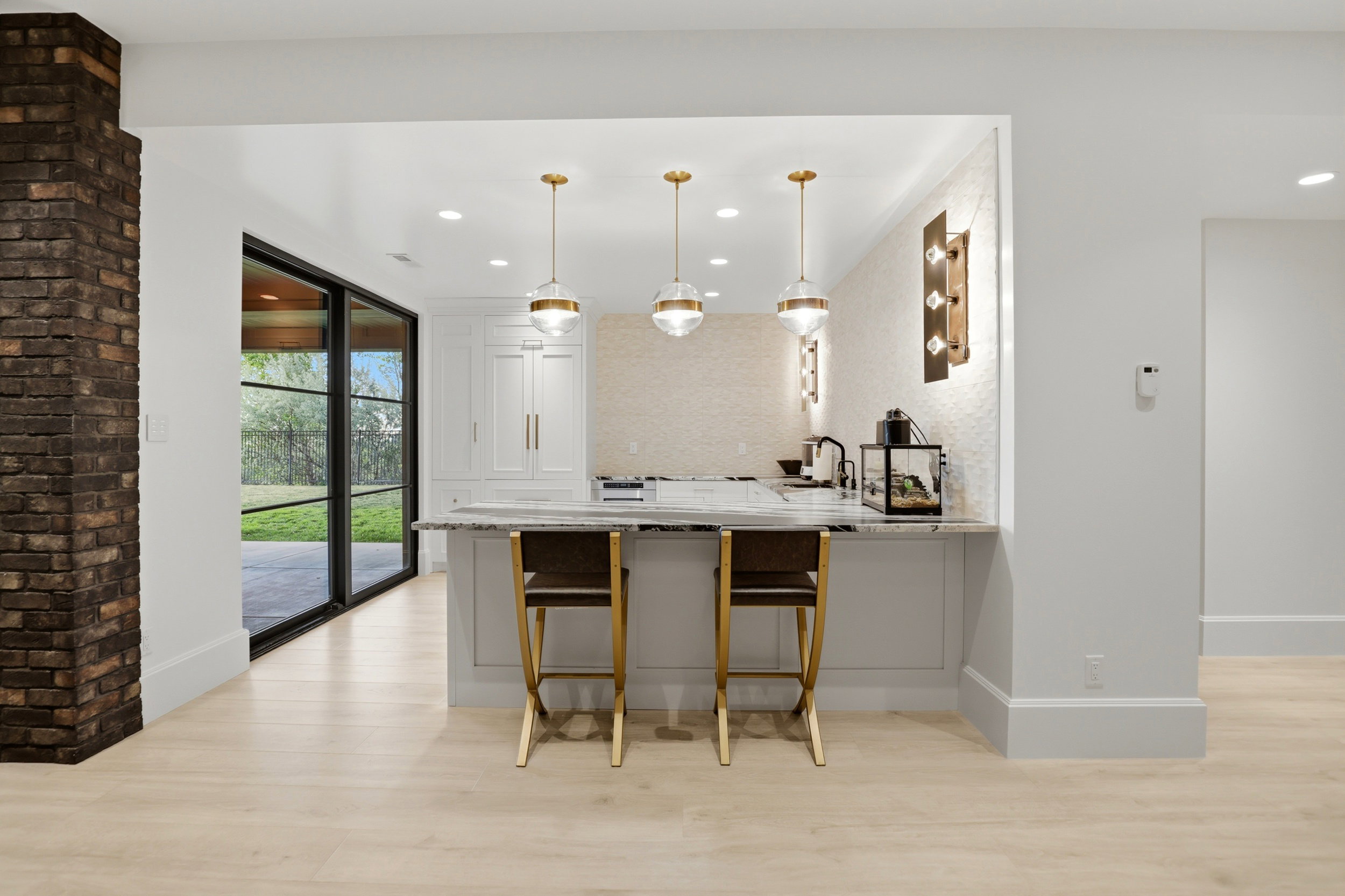 Kitchen with light wood-style flooring, a breakfast bar area, a peninsula, light stone countertops, and decorative light fixtures