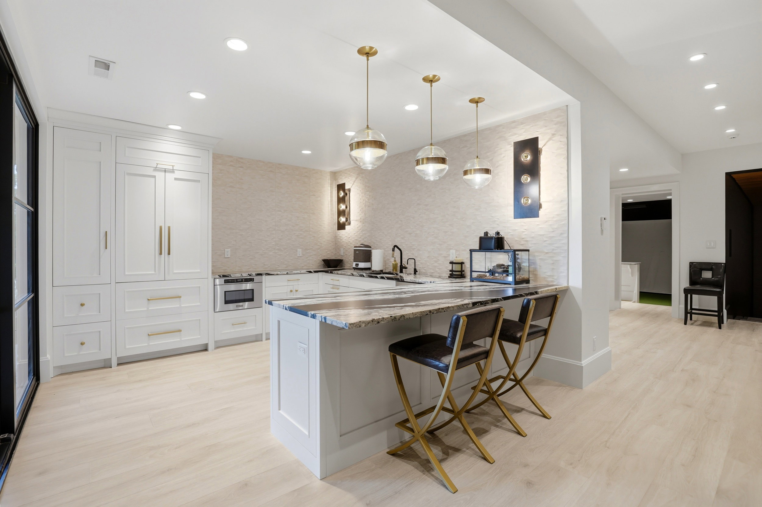Kitchen featuring light stone counters, pendant lighting, light wood-style floors, and a peninsula