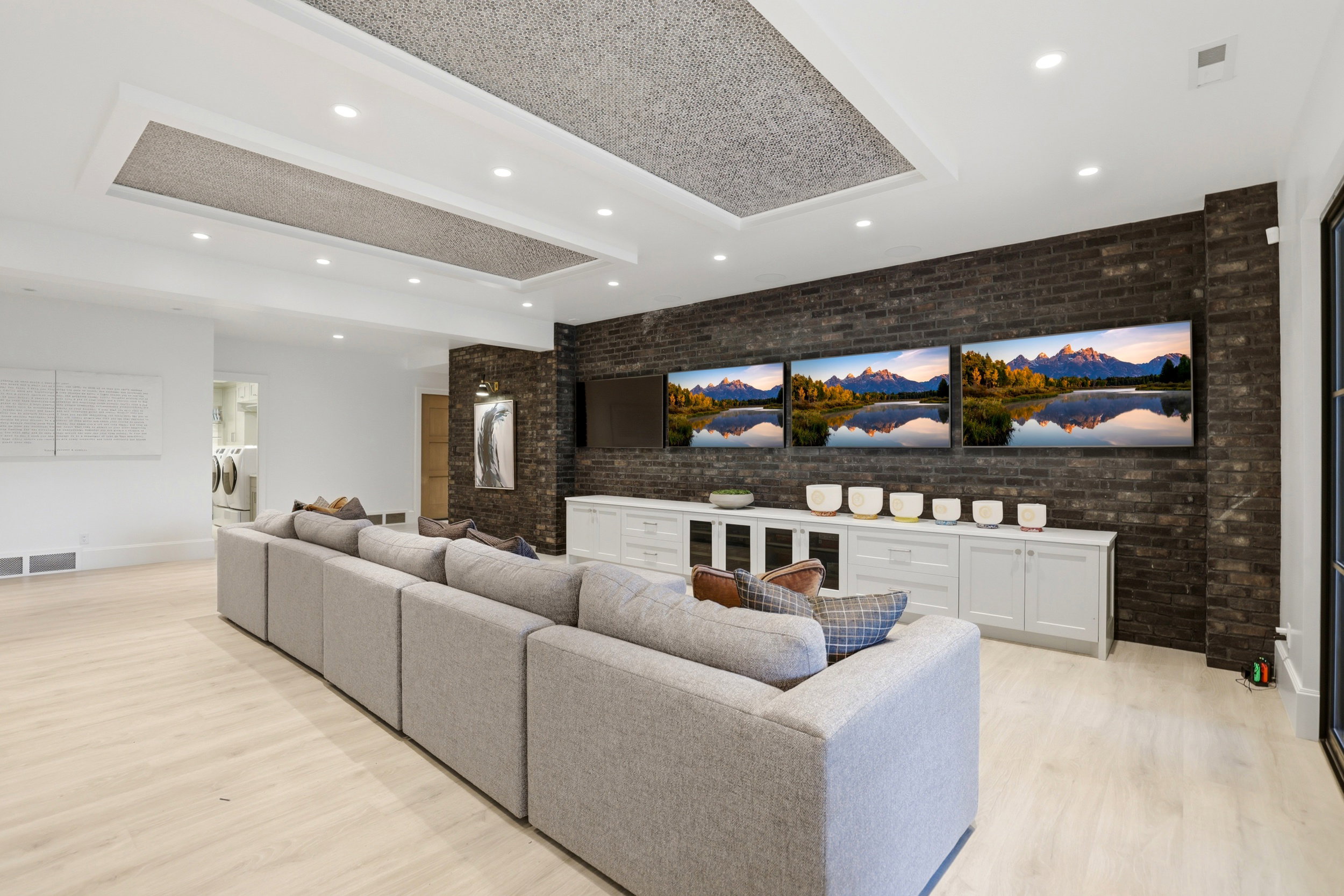 Living room featuring brick wall, light wood finished floors, recessed lighting, and a tray ceiling