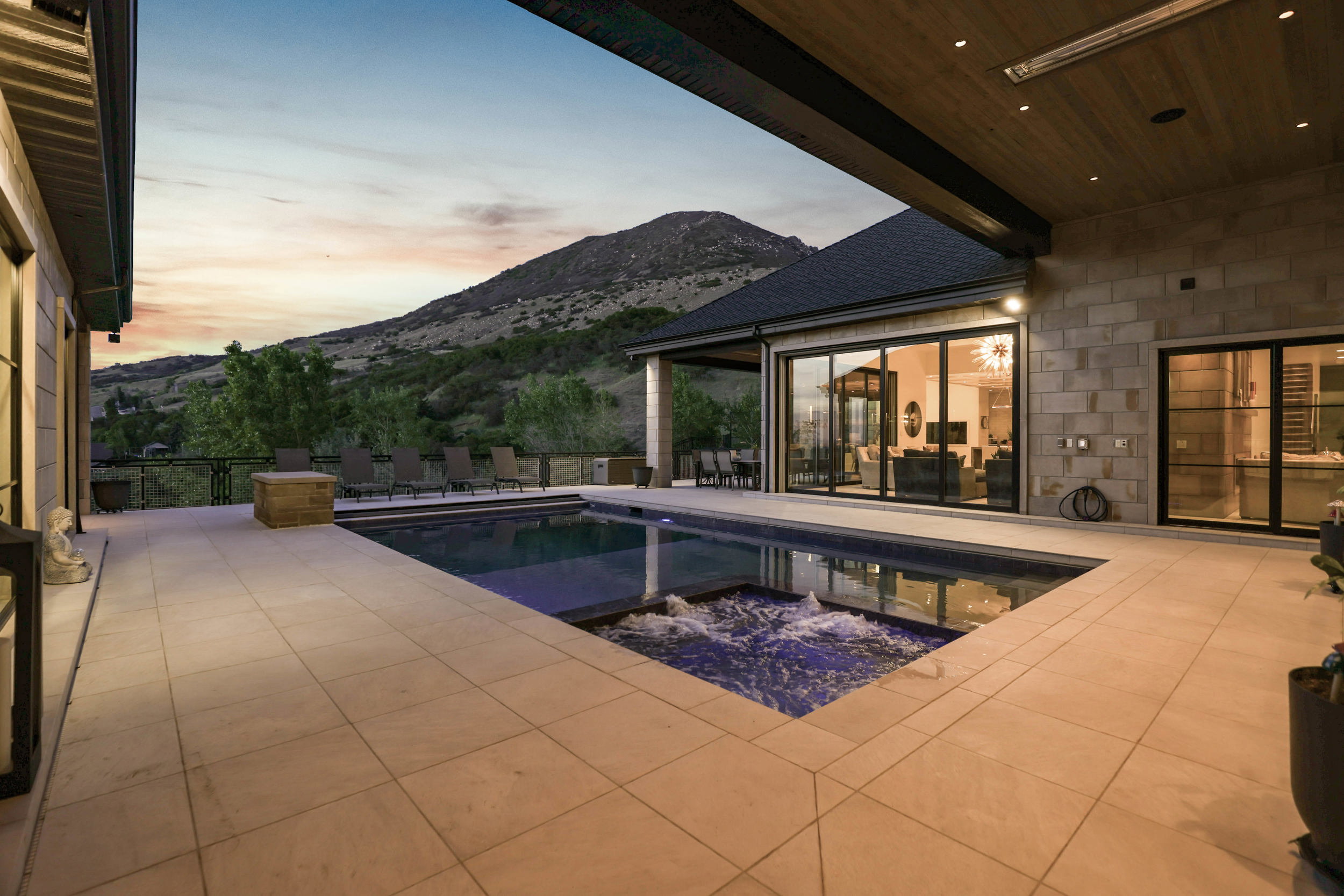 Pool at dusk with a patio, a mountain view, and a pool with connected hot tub